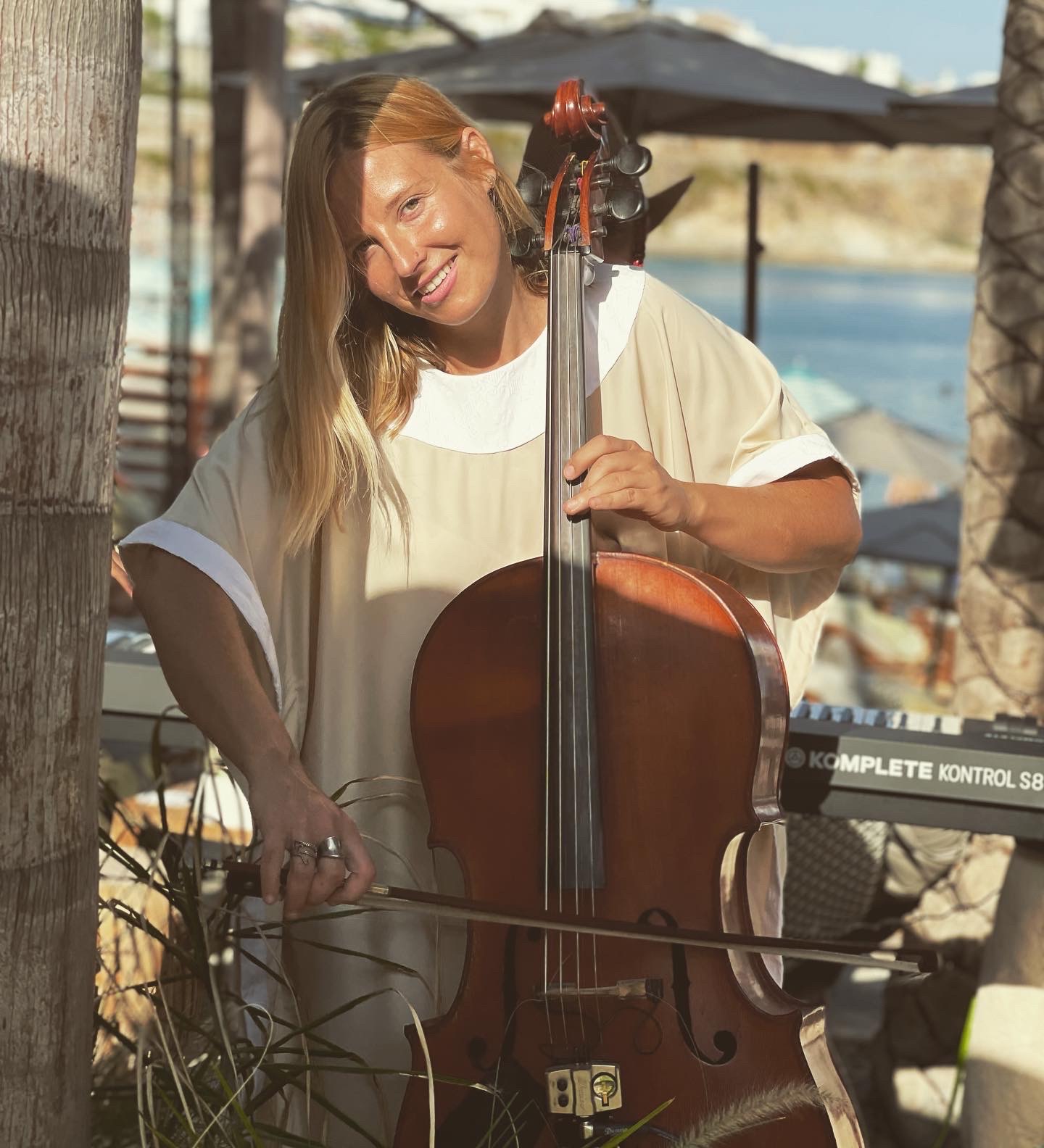 Cellist smiling with her cello in the sun