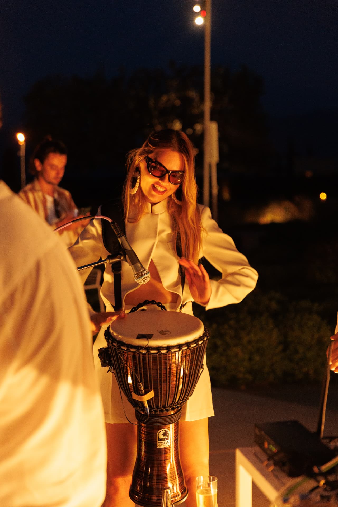 Percussionist in white playing the djembe at night at Amanzoe