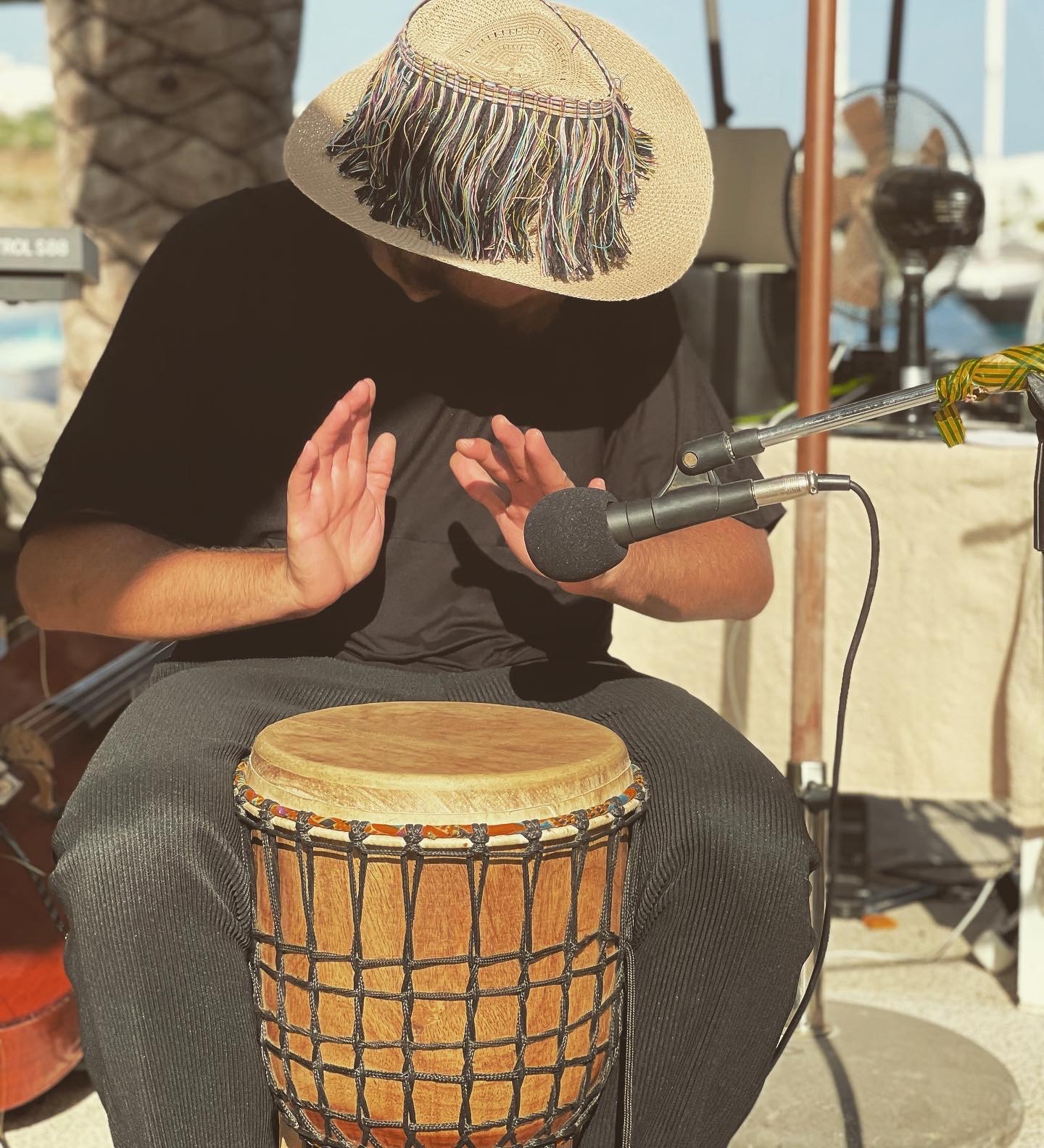 Percussionist in a fringed hat playing the djembe