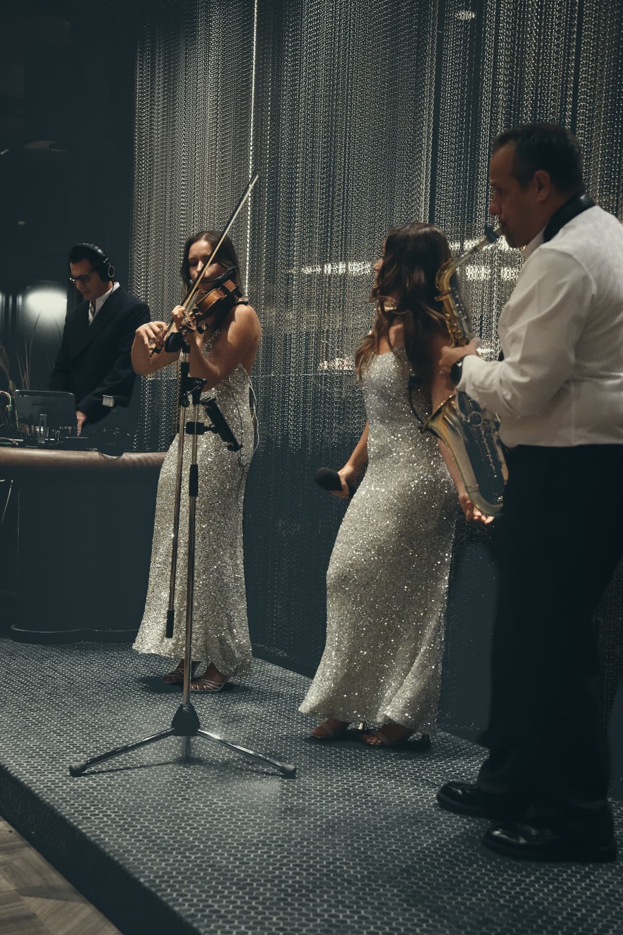 The band performing with violin, saxophone and DJ